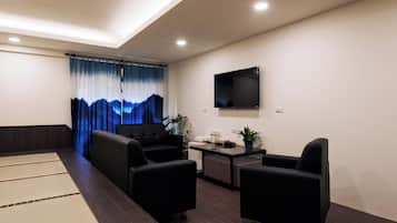 A modern living room with a sofa set, a coffee table, and a flat-screen TV mounted on the wall.