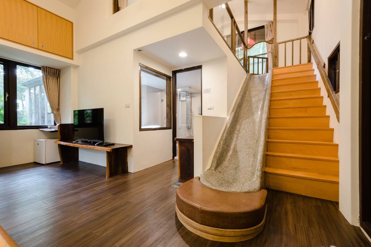 A modern interior with a wooden staircase, a flat-screen TV, and a small kitchenette area.