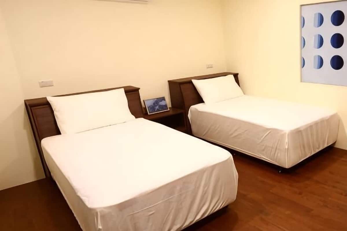 Two single beds with wooden headboards, a small bedside table, and a wall-mounted artwork.