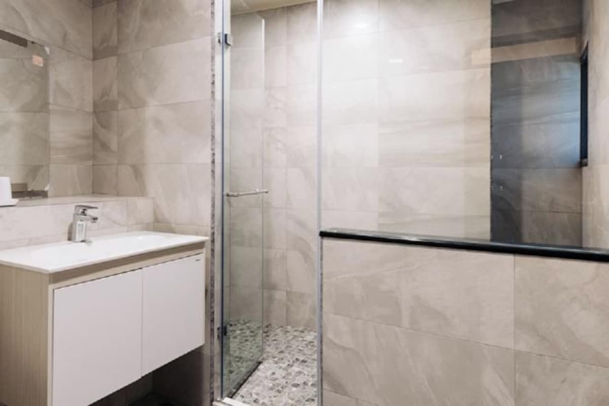 A modern bathroom with a glass shower enclosure, a white sink, and a wooden vanity.