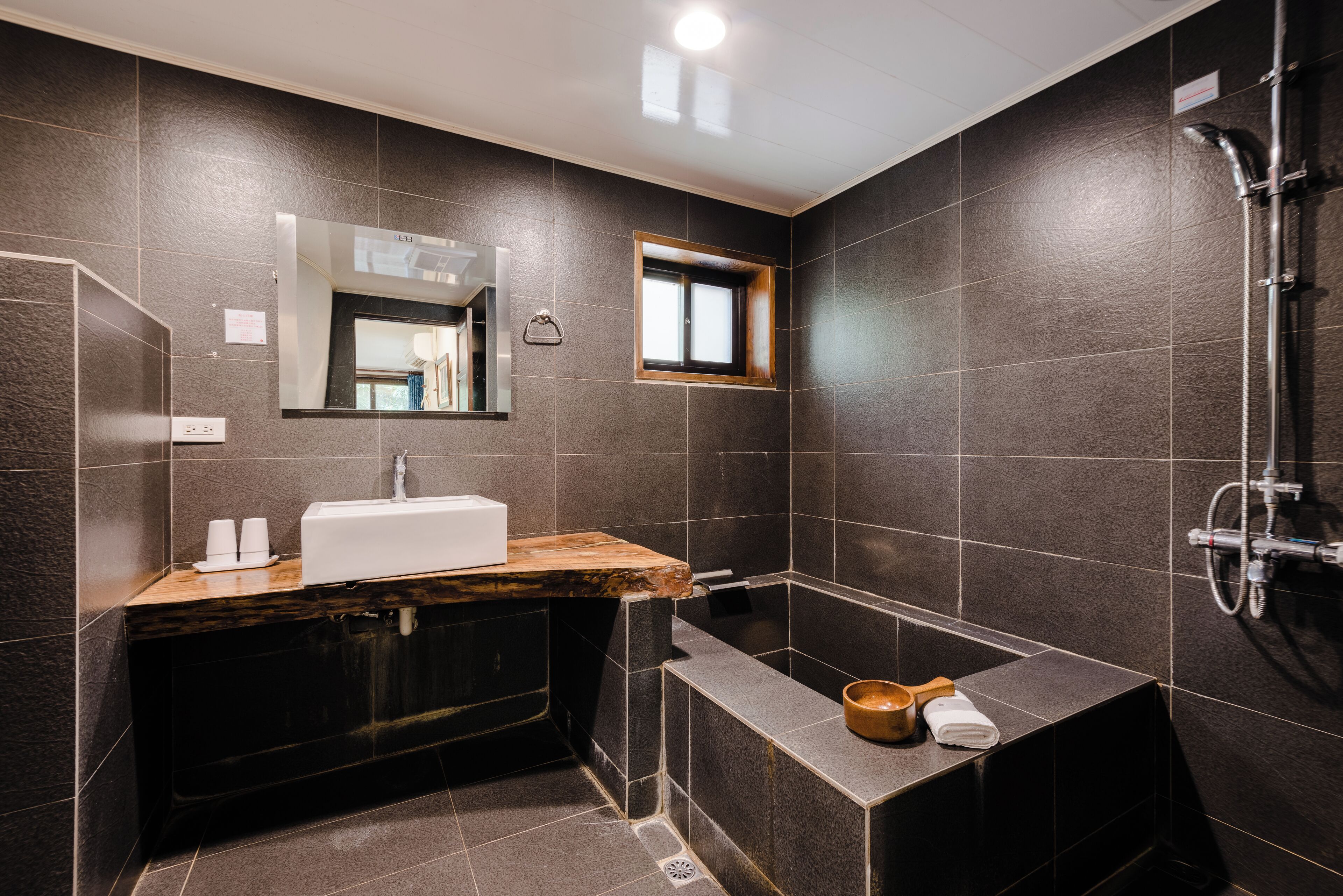 A modern bathroom with a large bathtub, a wooden vanity, a mirror, and a shower area.
