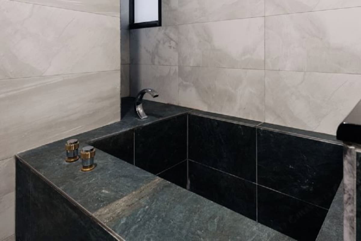 A modern bathroom with a black marble sink, a faucet, and a mirror.
