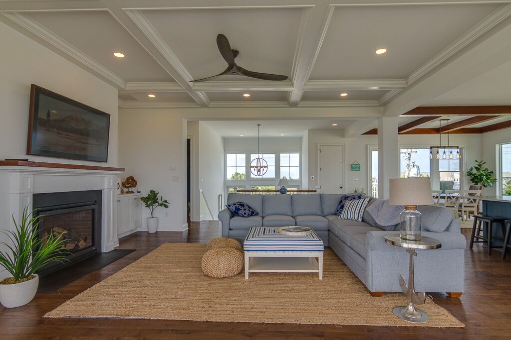 A spacious living room with a fireplace, a large sofa, and a dining area in the background.
