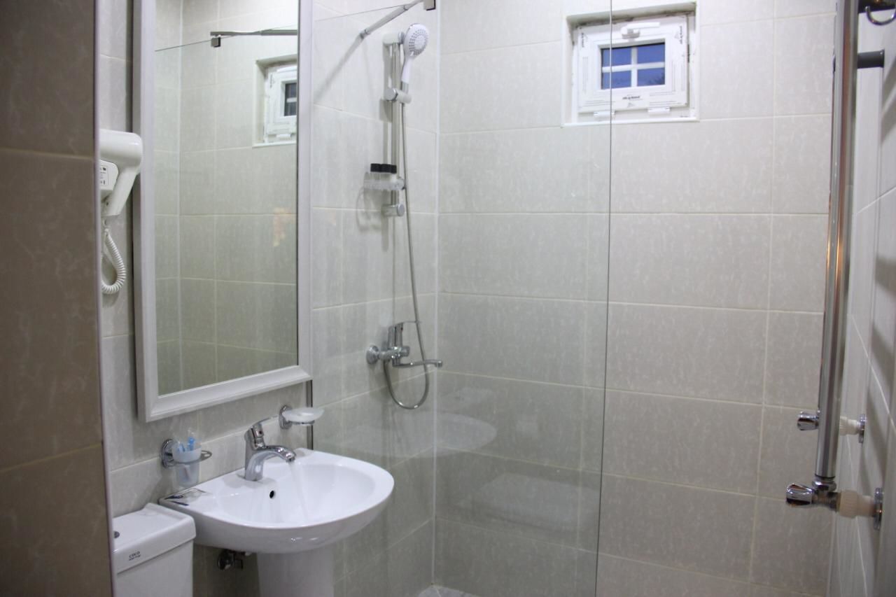 A bathroom with a white sink, a mirror, and a shower.