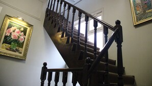 A staircase with wooden balusters and a handrail, flanked by framed floral paintings on the walls. - Old East Boutiques (Baku)