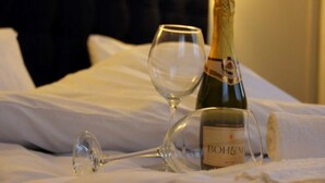 A bottle of Bohlmann wine and a wine glass on a bed with white linens. - Old East Boutiques (Baku)