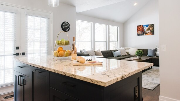 A modern kitchen with a large island, black cabinets, and a dining area with a sofa and a coffee table. - Large Home, 4 bds, 3.5 bths, complete remodeled: luxurious amenities..see pics (Cottonwood Heights)