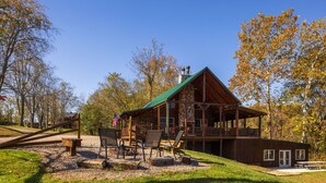 A lodge with a green roof, outdoor seating, and a deck.