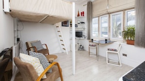 Una habitación pequeña con literas, un escritorio, una silla y una mesa de comedor.