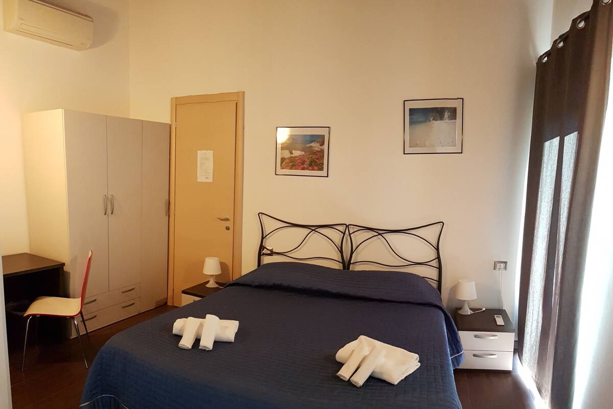 A bedroom with a bed, a wardrobe, a desk, and a chair.