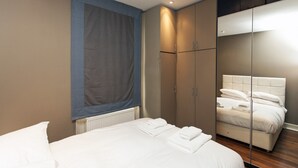 Ein modernes Schlafzimmer mit einem großen Bett, einem Kleiderschrank und einem Schminkspiegel.