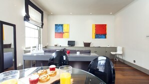 Eine moderne Küche mit Esstisch, gedeckt für ein Frühstück, mit Gebäck und Orangensaft.
