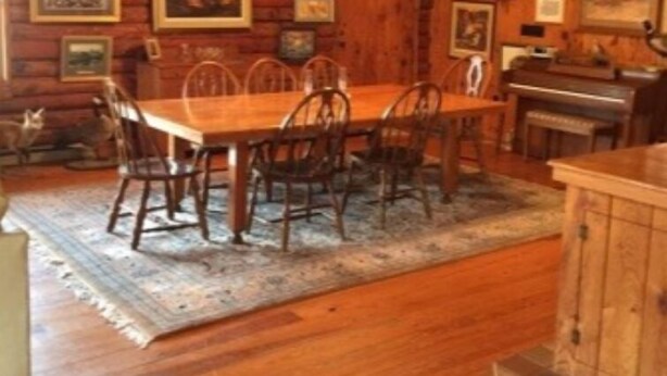 Un comedor de madera con una mesa y sillas, un piano y cuadros en las paredes.