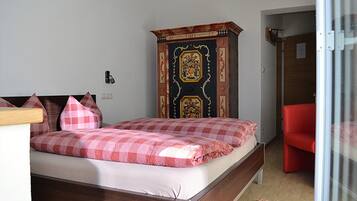 A bedroom with a bed, a red chair, a wardrobe, and a door.