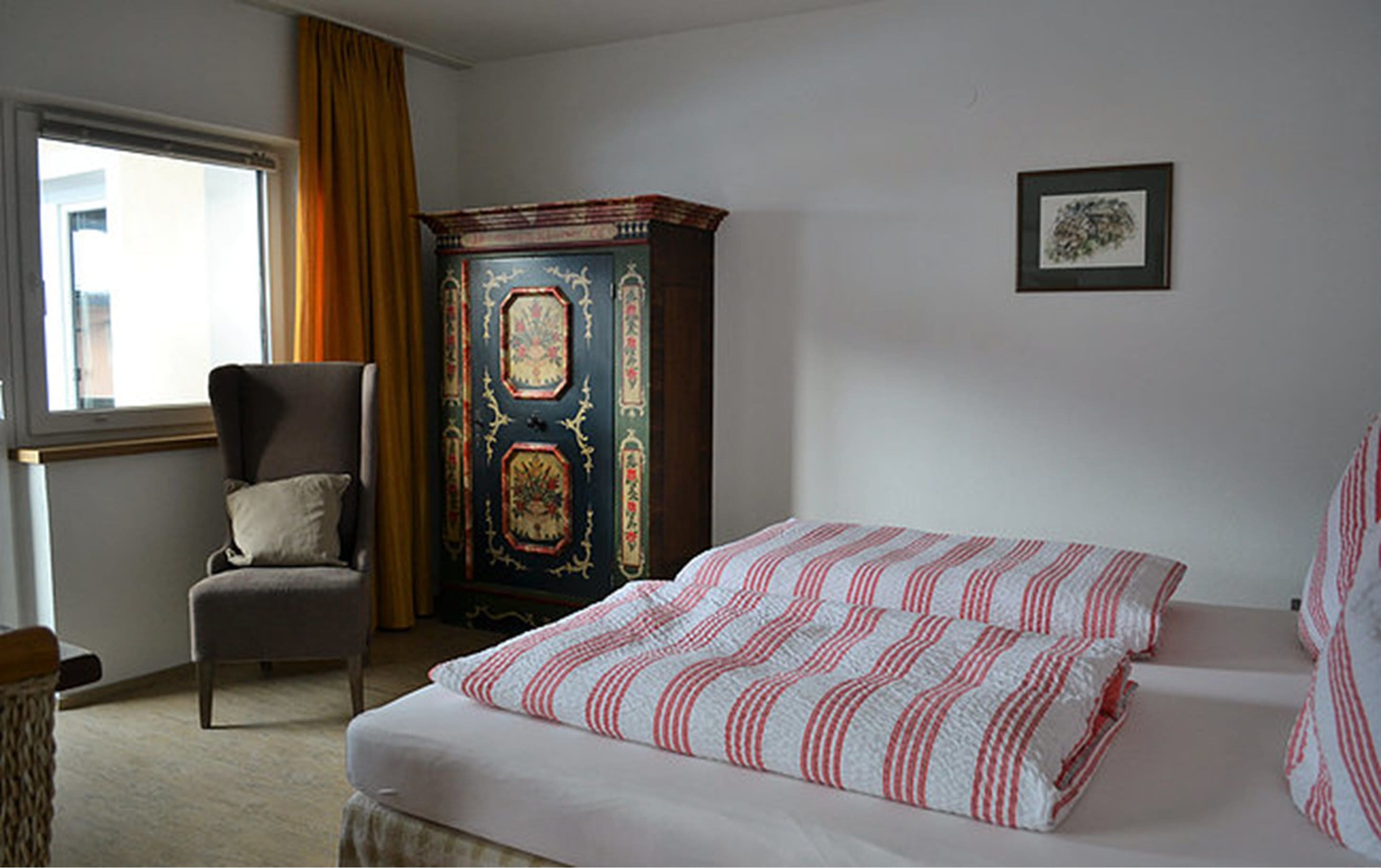 Ein Schlafzimmer mit Bett, Stuhl, Kleiderschrank und Fenster.