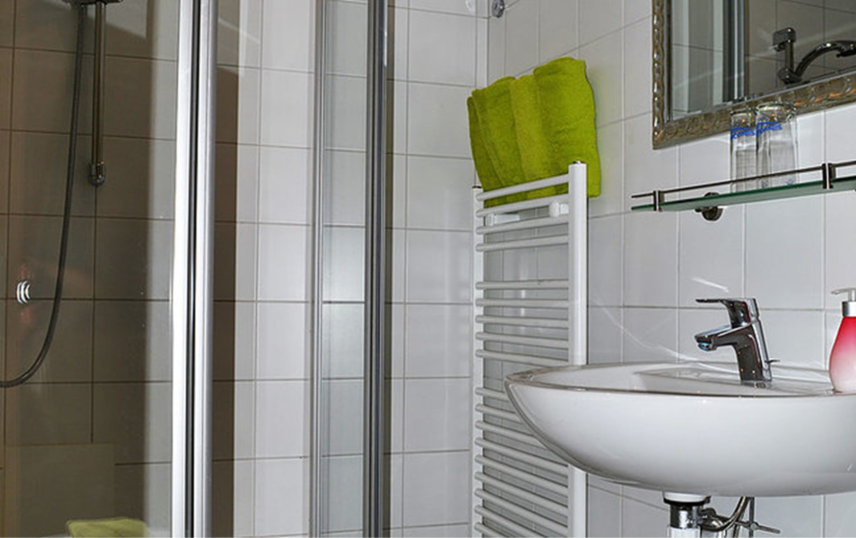 A bathroom with a shower, a sink, a mirror, and a towel rack.