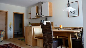 A modern kitchen with wooden cabinets, a dining table, and chairs.