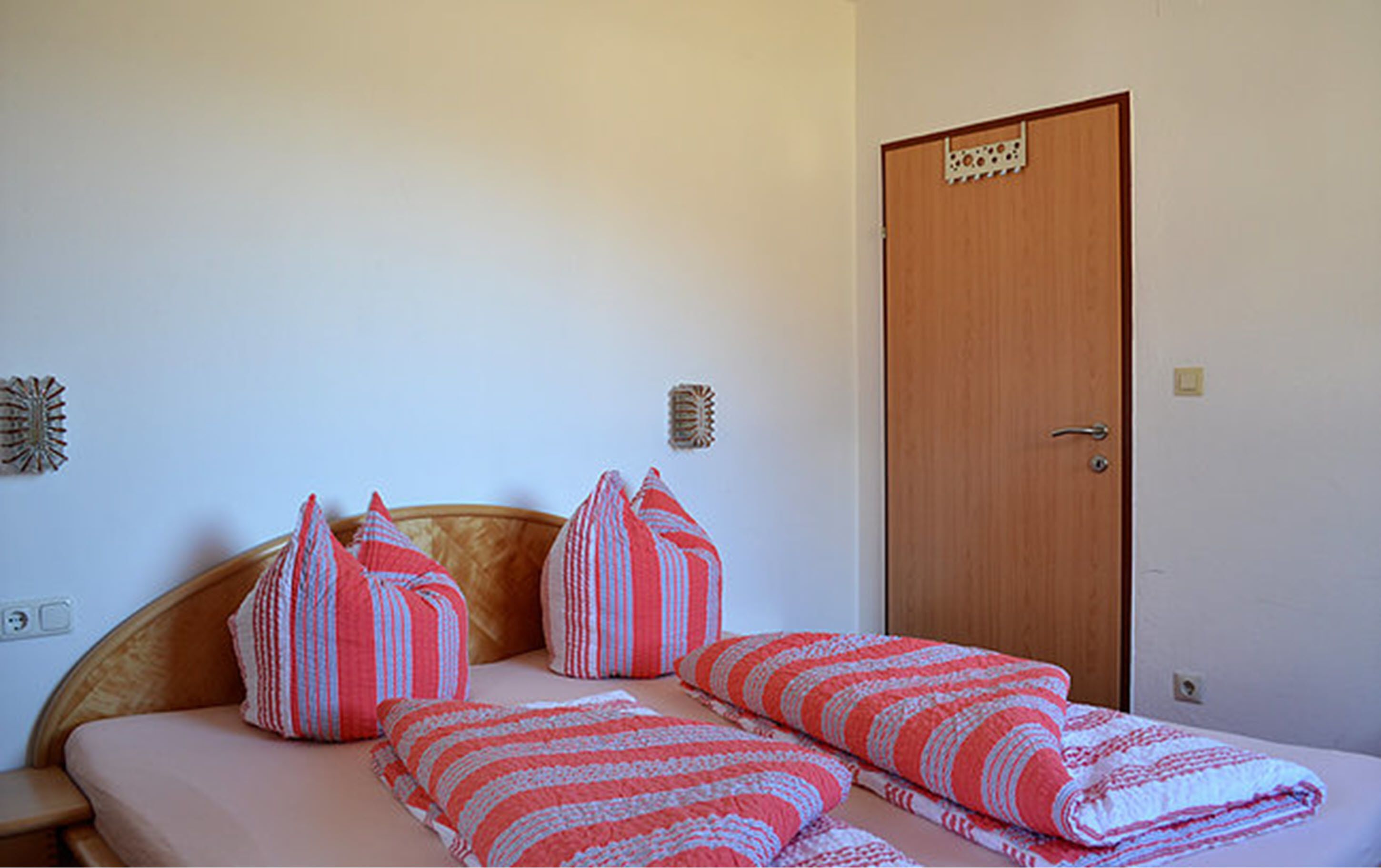 A bedroom with a bed, pillows, and a door.