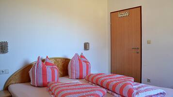 A bedroom with a bed, pillows, and a door.