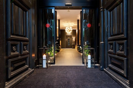 A hallway with dark wood paneling, a chandelier, and a carpeted floor.