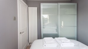 A hotel room with a bed, a wardrobe, and a door. - Shopping Centre and Cinema Atmosphere (London)