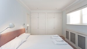 Hotellihuone, jossa on suuri sänky, yöpöytälamppu, vaatekaappi ja ikkuna.