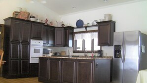 A kitchen with dark wooden cabinets, a stainless steel refrigerator, and a built-in oven. - Beautiful Getaway - Reynolds Farm Lodge  (Little Marsh)