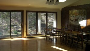 A spacious room with large windows, a wooden floor, and a dining area with chairs and a table. - Beautiful Getaway - Reynolds Farm Lodge  (Little Marsh)