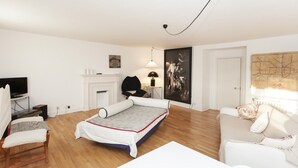 Quarto moderno e bem iluminado com cama, sofá, TV, lareira e um mapa na parede.