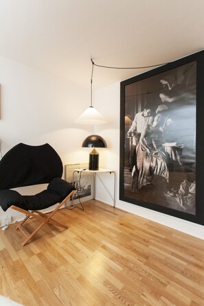 A modern room with a black chair, a small table with a lamp, and a large framed artwork on the wall. - South Kensington Italian Architect Home (London)