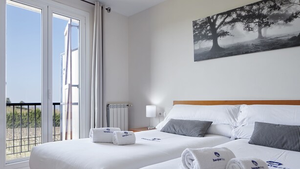 Habitación de hotel con dos camas, un balcón y un cuadro en la pared.