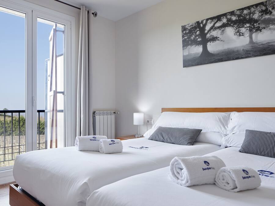 Une chambre d’hôtel avec deux lits, un balcon et un tableau au mur.