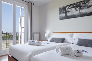 Habitación de hotel con dos camas, un balcón y un cuadro en la pared.
