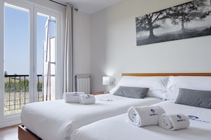 Habitación de hotel con dos camas, un balcón y un cuadro en la pared.