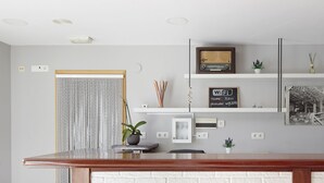 Una cocina moderna con encimera de madera, pared de ladrillo blanco y diversos objetos decorativos, incluyendo una radio antigua, una obra de arte enmarcada y un cartel de WiFi.
