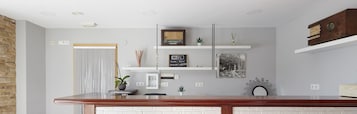 Una cocina moderna con encimera de madera, pared de ladrillo blanco y diversos objetos decorativos, incluyendo una radio antigua, una obra de arte enmarcada y un cartel de WiFi.