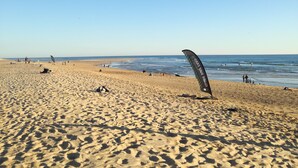 Une plage de sable fin, sous un ciel bleu azur et une mer calme.