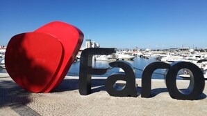 Un port de plaisance avec des bateaux, une sculpture rouge en forme de cœur et le mot « Faro » écrit en lettres noires.