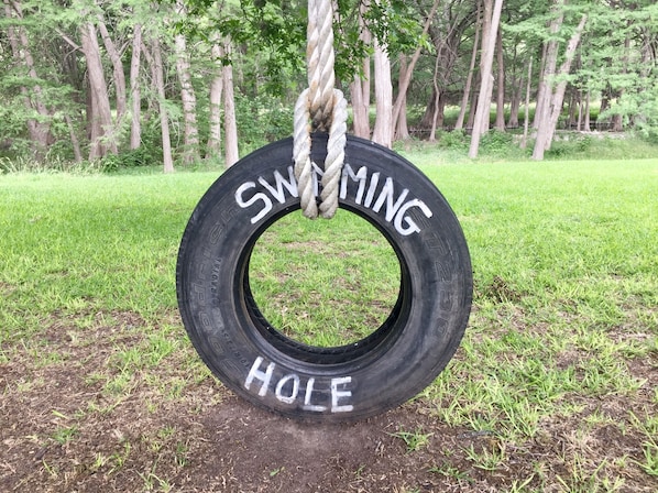 Une balançoire faite d’un pneu, sur laquelle on a écrit « ZONE DE BAIGNADE », et qui est suspendue à une corde.