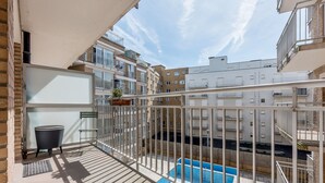 Un balcón con vista a una piscina, una planta en maceta y una pequeña mesa.
