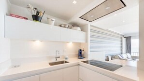 Una cocina moderna con armarios blancos, un lavamanos empotrado y una cafetera.
