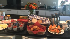 Een ontbijtbuffet met diverse gerechten, waaronder gebak, fruit en drankjes.