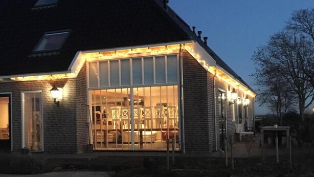 Een huis met een grote glazen voorgevel, een bakstenen buitenkant en een schuin dak.