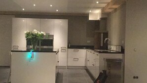 Een moderne keuken met witte kasten, een centraal eiland met een bloevas en een inbouwoven.