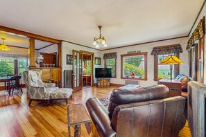 Relax in this stylish living room with a comfortable sofa, armchair, and large windows offering a view of lush greenery.