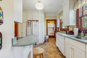 Kitchen features a dishwasher, refrigerator, and stool.