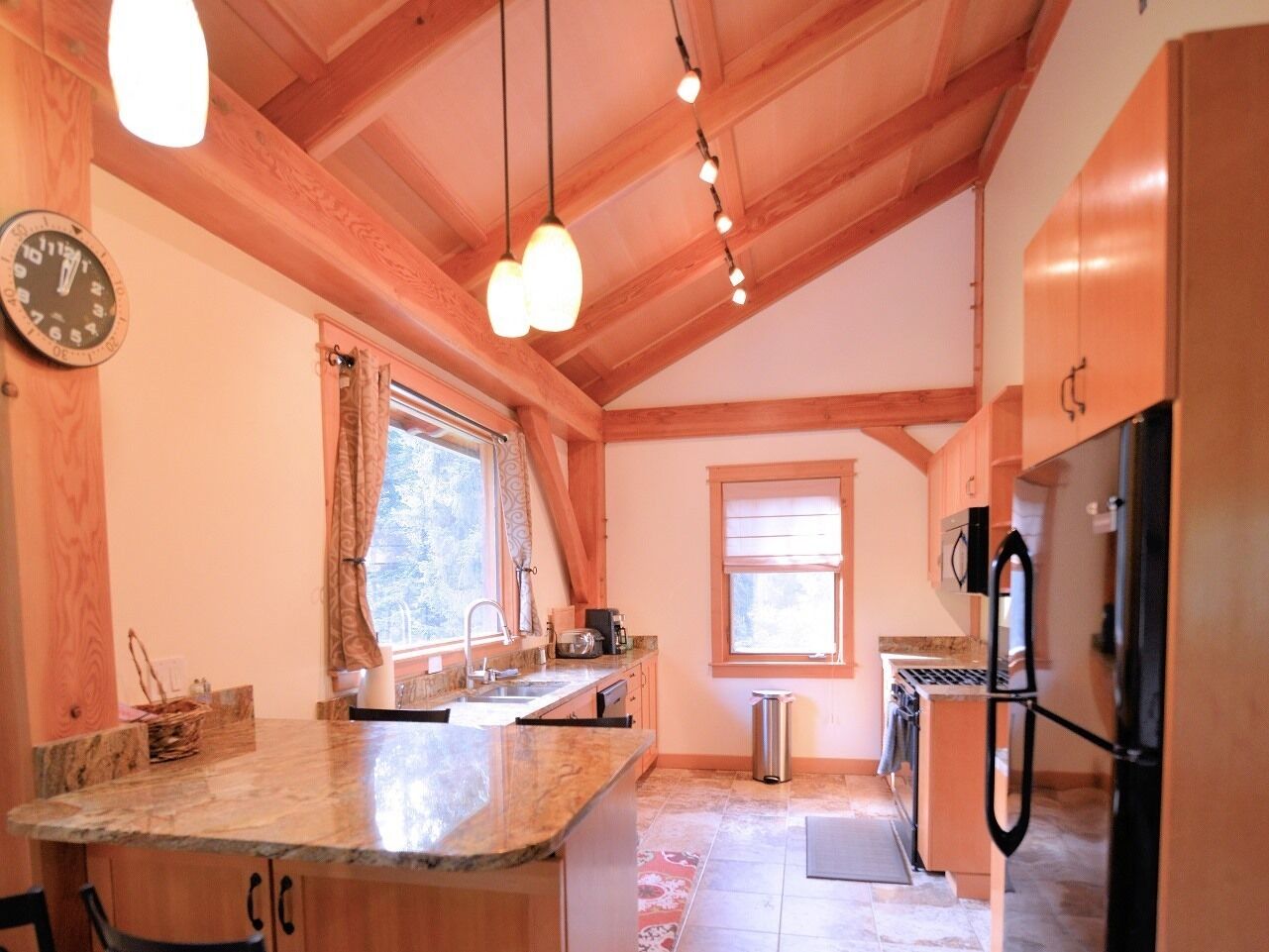 Una cocina con vigas de madera, un fregadero, un refrigerador y una ventana con cortinas.