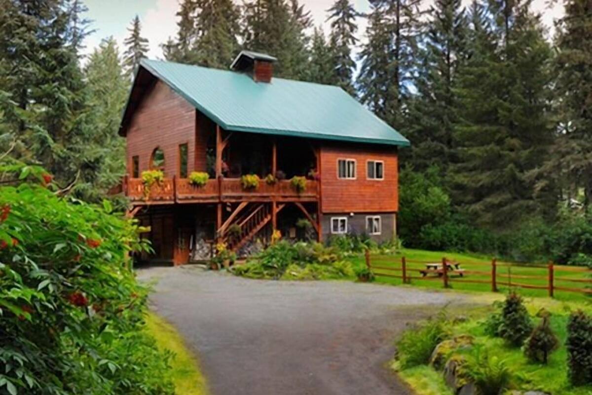 Eine rustikale Holzhütte mit grüner Dachdeckung, einer Holzdiele und einem Steinfundament.