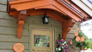Una casa de madera con porche, una puerta y una cesta de flores colgante.