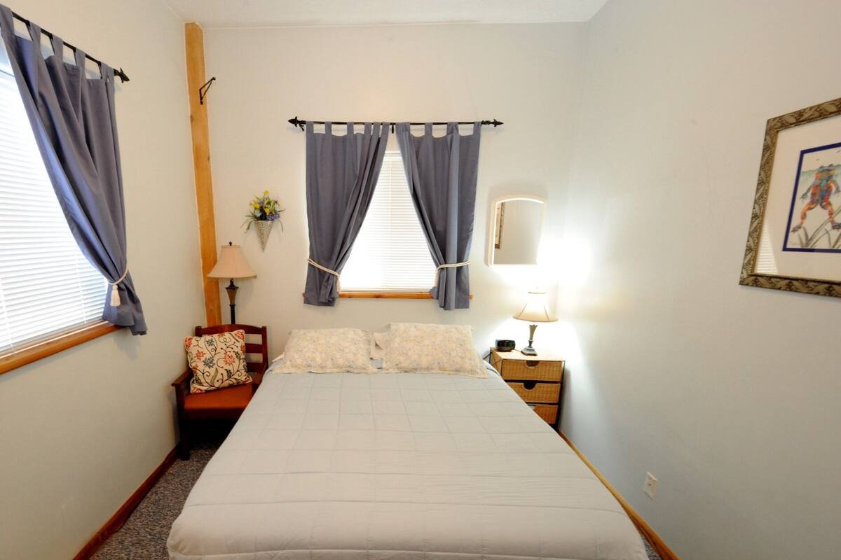 Ein Schlafzimmer mit Bett, Nachttisch, Lampe und einem gerahmten Bild an der Wand.